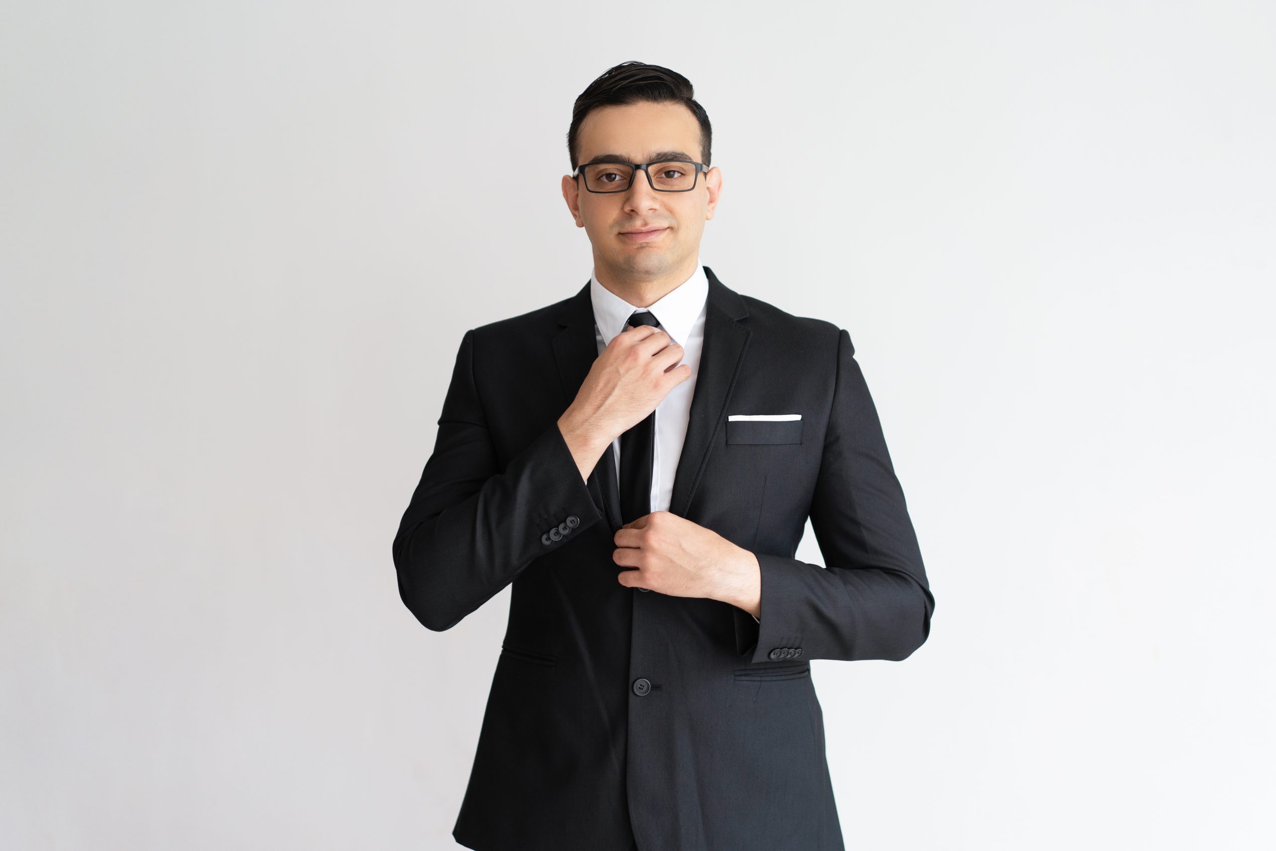 Confident stylish handsome young businessman adjusting necktie Confident stylish handsome young businessman adjusting necktie and looking at camera. Content rich man in expensive black suit getting ready for work. Business style concept